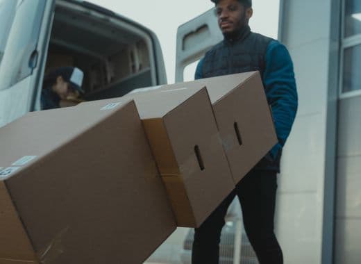 Mover carrying stacked cardboard boxes away from a van