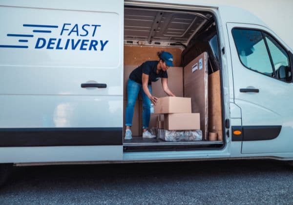 Courier arranging parcels inside the side door of a delivery van